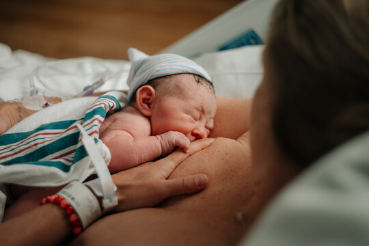 A newborn baby begins to breastfeed on her mother in a hospital.
