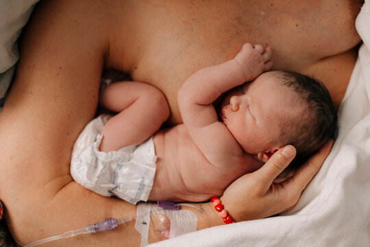 A newborn baby rests in her mother's arms in the hospital.