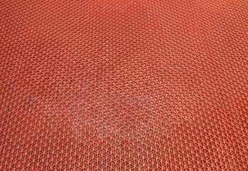 Obraz premium A wet orange anti-slip plastic mat or hollow mesh rubber carpet, featuring water droplets and a repeating geometric pattern