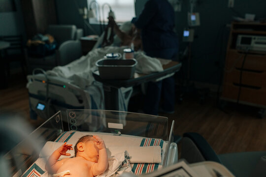 A newborn baby rests on a blanket in the hospital.