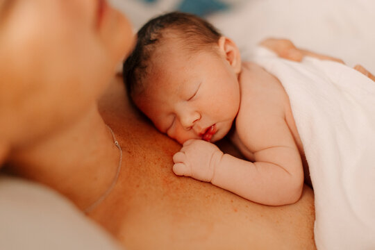 A newborn baby rests on a her mother's chest in the hospital.