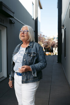 Candid portrait of a senior woman in denim jacket walking urban roads