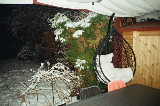 Snowy backyard terrace with a hanging egg chair at night