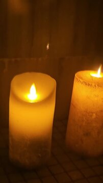 Candle flames flicker in a dimly lit setting