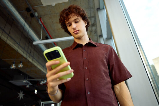 Young Man Using Smartphone in a Modern Workspace