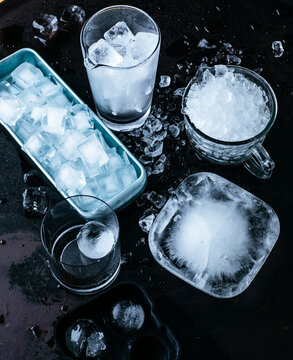 Ice in various containers on a dark surface at a cocktail bar