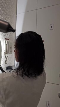 Drying wet hair with a hairdryer in a bathroom setting