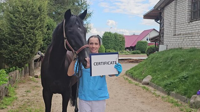 Person standing with a horse while holding a certificate in a rural setting