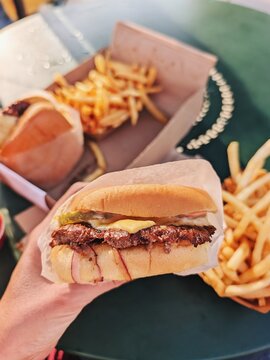 Juicy Burger With Fries at Outdoor Table on Sunny Day