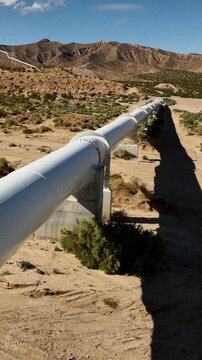 Aerial shot of the Los Angeles Aqueduct as it passes over some low mountains in California. The aqueduct supplies water to Los Angeles and Southern California. Vertical video.