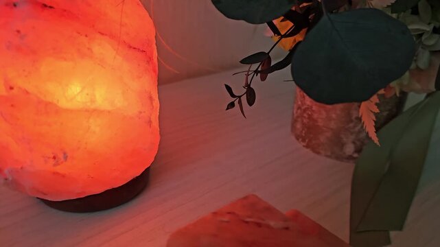 Warm glow of a salt lamp beside plants on a white table in a cozy room