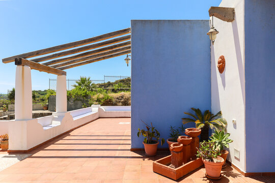 Blue wall terrace with pergola and potted plants