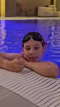 Child enjoying pool time with swim goggles and giving a thumbs up