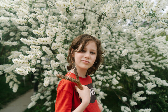 Kid  holding slingshot among spring blossoms