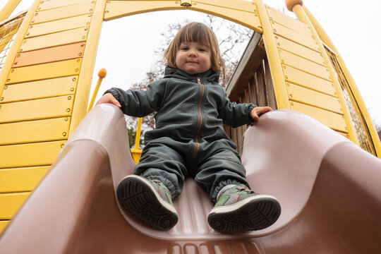 Child Playing on a Slide at a Playground on a Cloudy Day