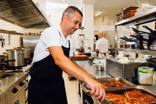 Cook placing roasted meat trays
