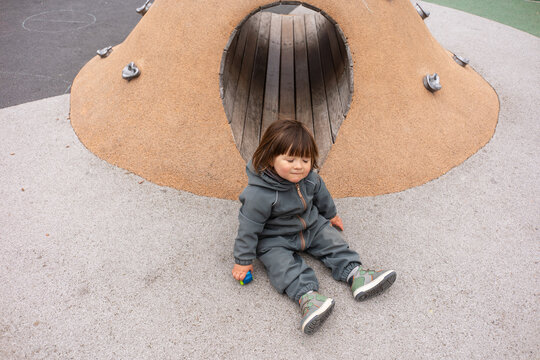 Child Playing Near a Playground Structure on a Sunny Day
