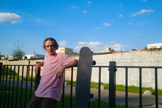 Skateboarder Portrait Leans On Fence in Urban Area During Training