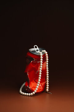 Pearl necklace hanging inside from a red metal soda can