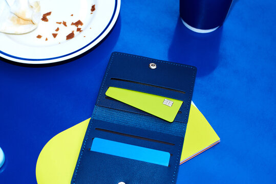 A wallet with a lime-colored card on a blue table in a caf&eacute;.