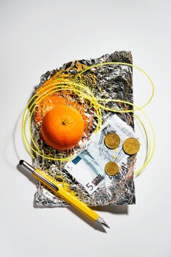 Money, orange, yellow filament and pen on piece of aluminum foil