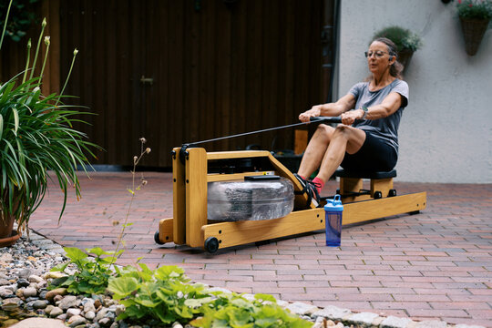 middle aged women working out outdoors with rowing fitness machine