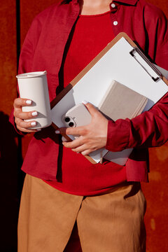 Woman balancing office essentials with coffee in warm sunlight