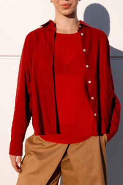 Woman wearing layered red shirt and sweater in bright sunlight