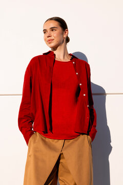 Confident woman in bold red layers posing in direct sunlight