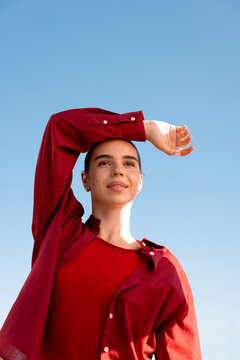 Woman in layered red clothing against a clear blue sky