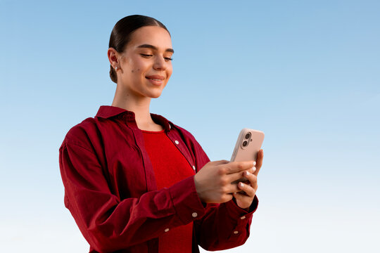 Woman using smartphone against clear sky in red shirt