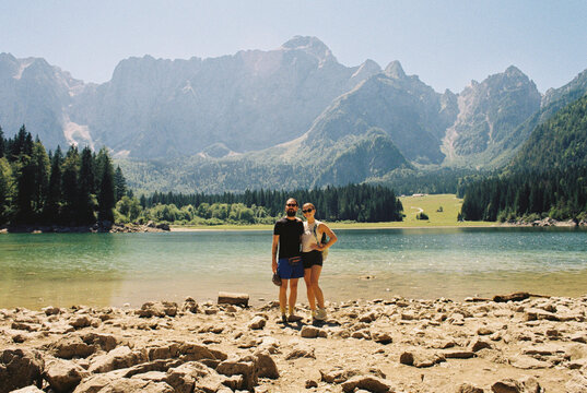 Couple poses for a photograph by a glacial lake in the Dolomites