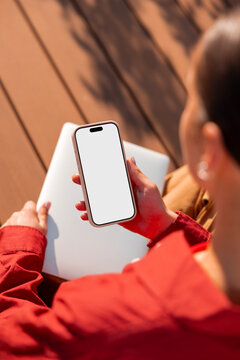 Woman holding smartphone mockup with blank screen at desk