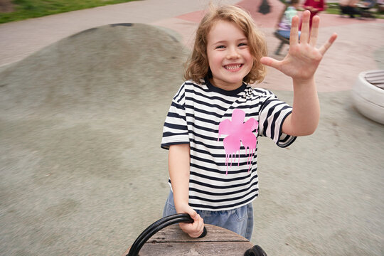 Child plays at a playground and shows five fingers