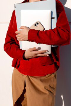 Woman carrying laptop, smartphone and folders for mobile work
