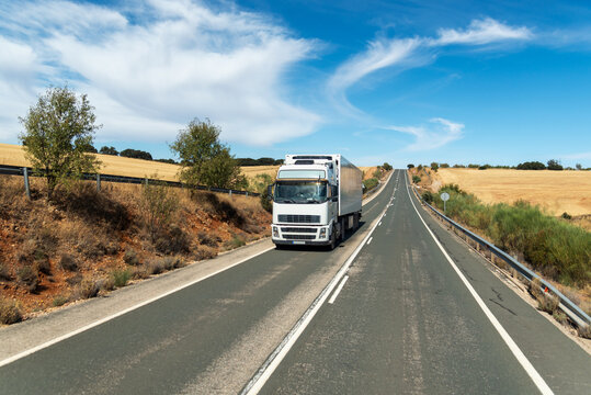 Refrigerated truck driving on a rural road through farmland