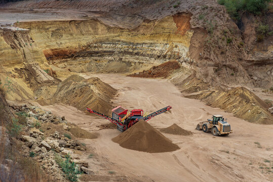 Industrial sand sorting machine and wheel loader working together in a stone quarry
