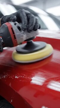 An Expert Technician Polishing a Red Car's Surface to Achieve a Perfect Shine and Enhance Its Overall Appearance in a Professional Auto Detailing Setting