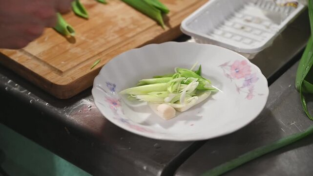 Sliced Green Garlic Sprouts Transferred to a White Ceramic Plate