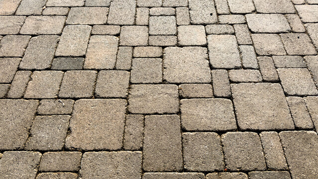interlocking rectangular and square stone pavers create a textured patio pavement under bright daylight