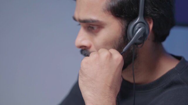 Businessman wearing headphones, is providing customer service online using a computer and AI powered management system. Call center sales, and customer communication. Coworking, telemarketing