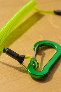 A shiny green climbing carabiner is resting on a wooden table