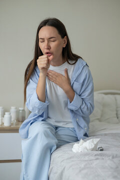 Sick woman resting in bed with symptoms of fever, runny nose and cough during an illness