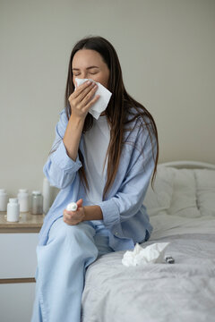 Sick woman resting in bed with symptoms of fever, runny nose and cough during an illness