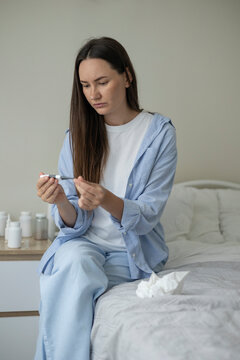 Sick woman resting in bed with symptoms of fever, runny nose and cough during an illness