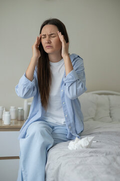 Sick woman resting in bed with symptoms of fever, runny nose and cough during an illness