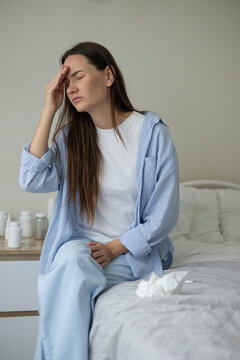 Sick woman resting in bed with symptoms of fever, runny nose and cough during an illness