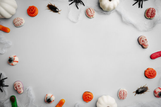 A modern greeting card for Halloween. Pumpkins, cobwebs, spiders, bats and candies, a ghost on a fashionable blue background. A banner with a place to copy the text. Top view. Flat Lay.