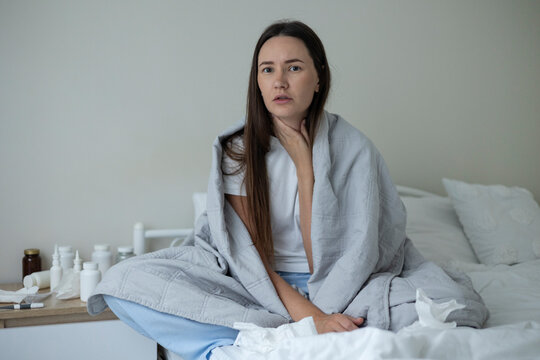 Sick woman resting in bed with symptoms of fever, runny nose and cough during an illness