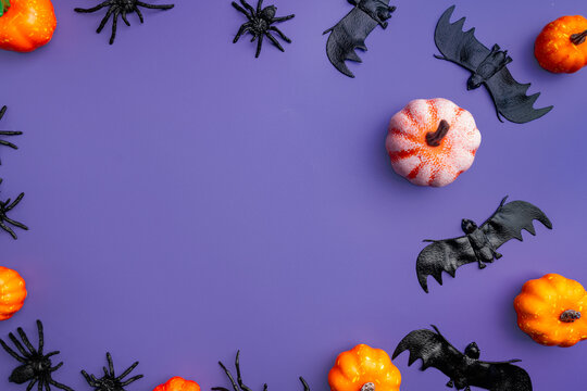 A modern greeting card for Halloween. Pumpkins, cobwebs, spiders, bats, a ghost on a fashionable purple background. A banner with a place to copy the text. Top view. Flat Lay.